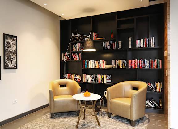 A room with a white table and two chairs in front of a bookshelf.