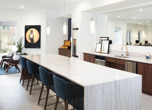 a large white kitchen with a long island and blue chairs