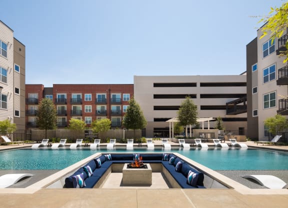 a swimming pool with lounge chairs in front of an apartment building