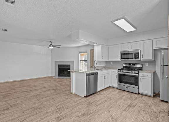 A spacious kitchen with a wood floor and white appliances.