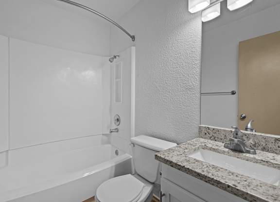 A white bathroom with a toilet, sink, and bathtub.