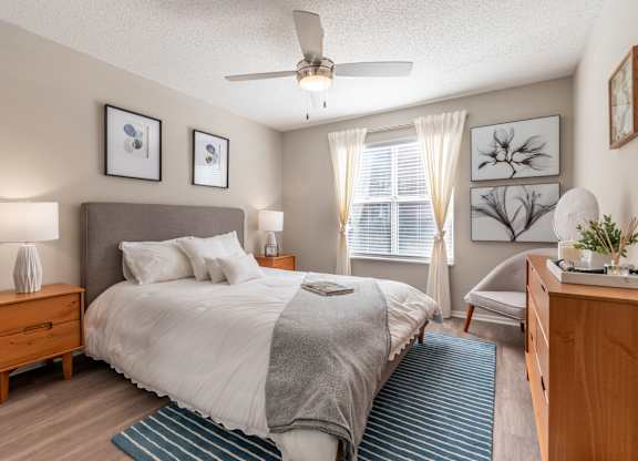 A bedroom with a bed, nightstand, and a ceiling fan.