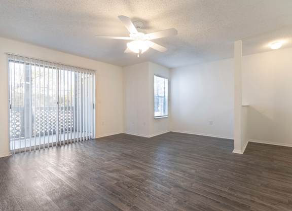 A room with a ceiling fan and a window with blinds.