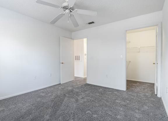 A room with a ceiling fan and carpeted floor.