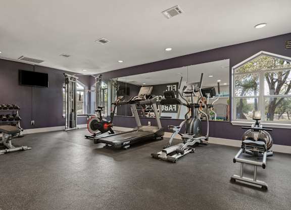 a home gym with a purple accent wall and a large window