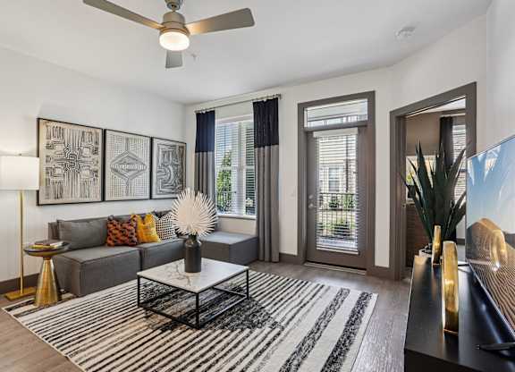 A living room with a grey couch, a coffee table, and a ceiling fan.