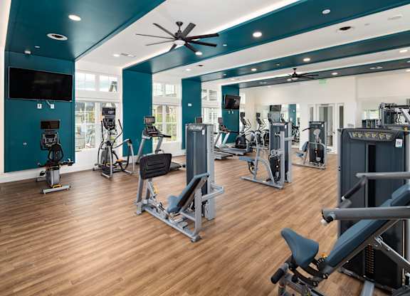 A gym with a variety of equipment including treadmills, weights, and exercise machines.