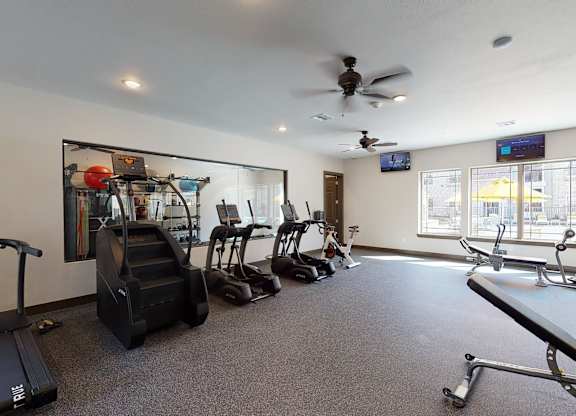 A gym with treadmills, elliptical machines, and other exercise equipment.