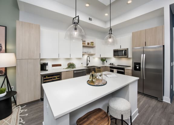 an open kitchen with a large white island and stainless steel appliances