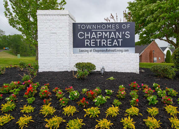 A sign for the Townhomes of Chapman's Retreat is surrounded by flowers.