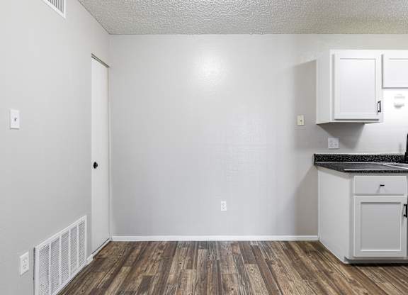 A kitchen with white cabinets and a black countertop.
