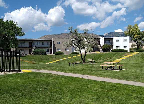 a grassy area with trees and buildings in the background