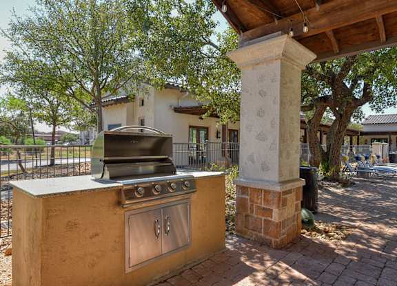 A brick pillar stands next to a stove in a sunny outdoor area.