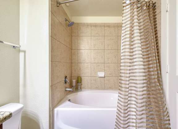 A bathroom with a white tub and a shower curtain.