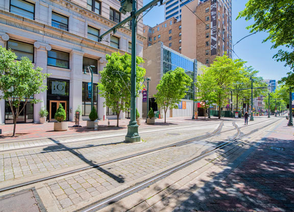 a city street with streetcar tracks and a building in the background