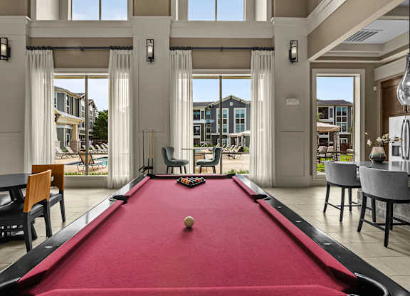 A pool table in a room with a view of the outside.