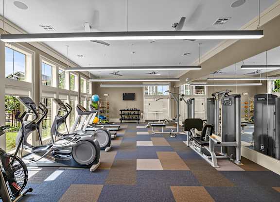 A gym with a variety of equipment including treadmills, stationary bikes, and weight machines.