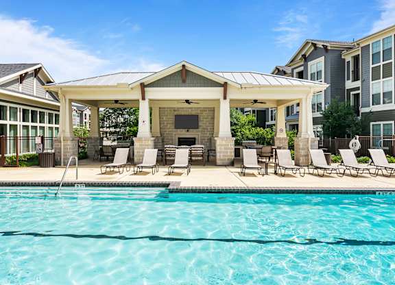 A swimming pool with a pavilion and chairs around it.