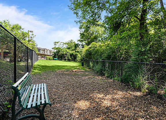 A park with a bench and a fence.