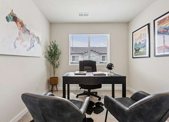 A room with a desk, chairs, and pictures on the wall.