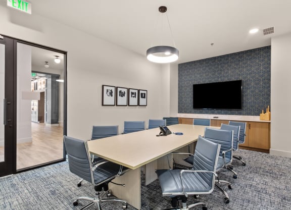a conference room with a long table and chairs and a tv