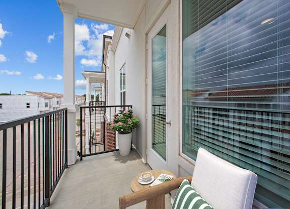 A balcony with a table, chairs and a potted plant.