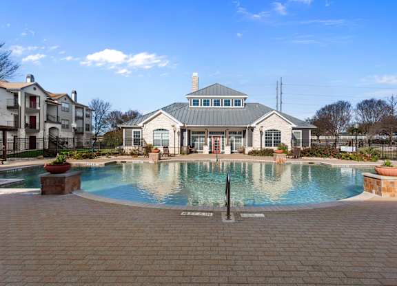 A large swimming pool in front of a building with a fountain in the middle.