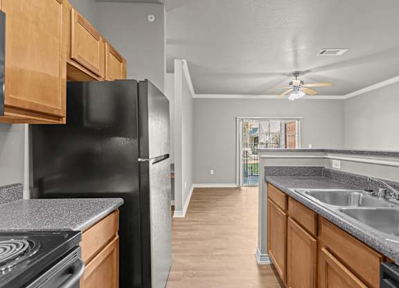 A kitchen with a black refrigerator and wooden cabinets.