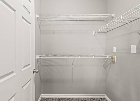 A white pantry with a white door and shelves.