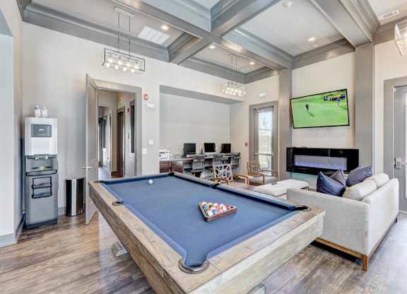 A pool table is in the middle of a room with a couch and a TV.