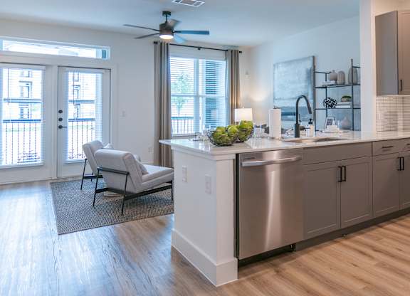 A modern kitchen with a large island and a balcony with a chair.