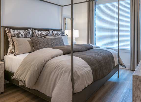 A bedroom with a large bed and a nightstand with a lamp.