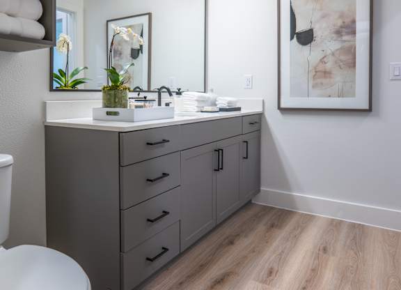 A bathroom with a toilet, sink, and mirror.