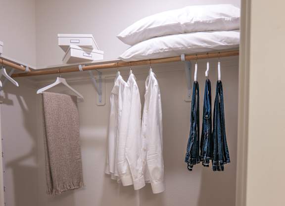 A white shirt is hanging on a hanger in a closet.