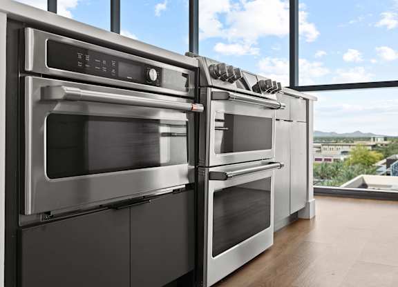 A row of modern stainless steel ovens in a kitchen.
