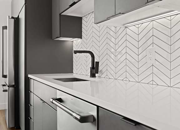 A modern kitchen with a black fridge and a white sink.