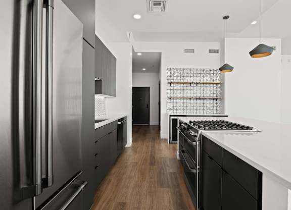 A modern kitchen with a stainless steel refrigerator and black cabinets.