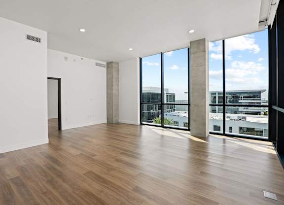 A room with wooden floors and a view of the city through large windows.