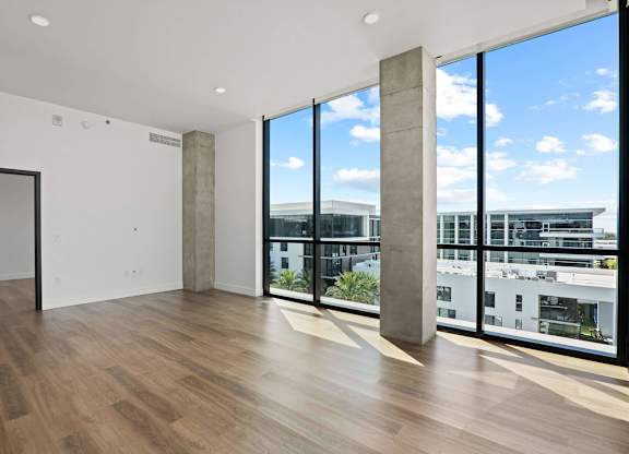 A room with a wooden floor and a view of the city through the windows.