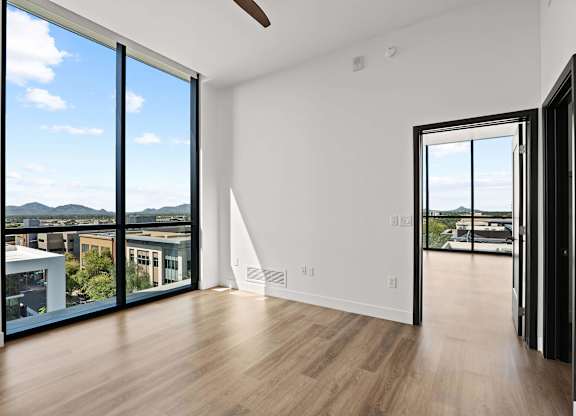 A room with a sliding glass door leading to a balcony with a view of the mountains.