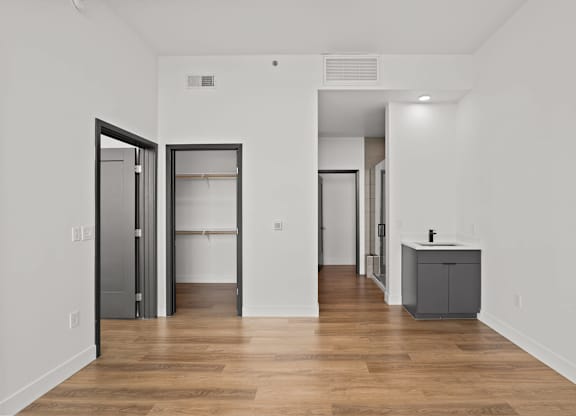 A room with a wooden floor and white walls with a grey cabinet and a wardrobe.