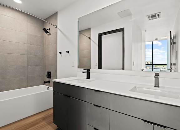 A modern bathroom with a white sink and black cabinets.