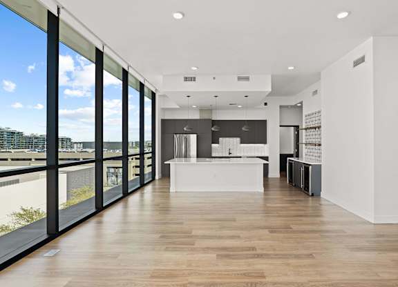A modern interior with a long wooden floor and a view of the outdoors through large windows.