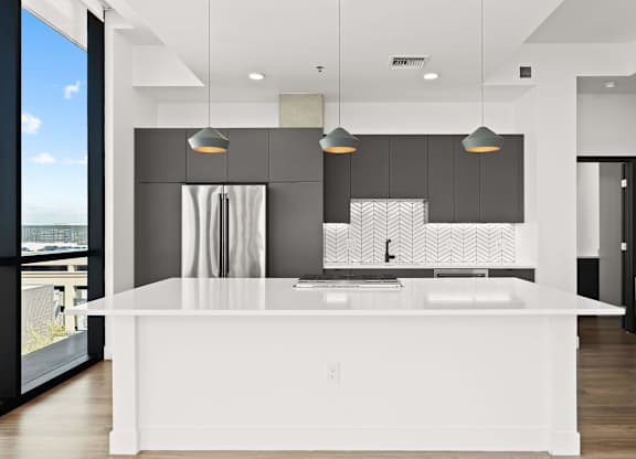 A modern kitchen with a large island and pendant lights.