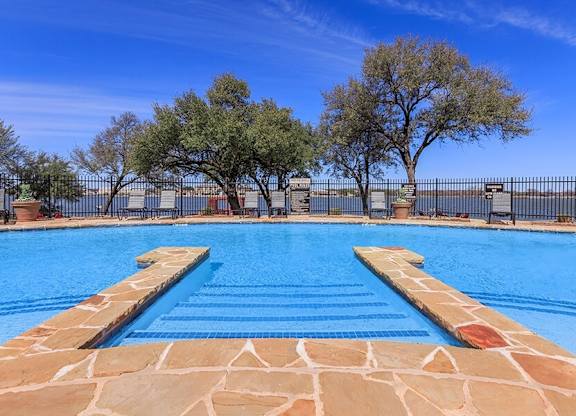 A swimming pool with a stone border and steps leading into the water.