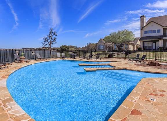 A large outdoor swimming pool surrounded by a stone border.