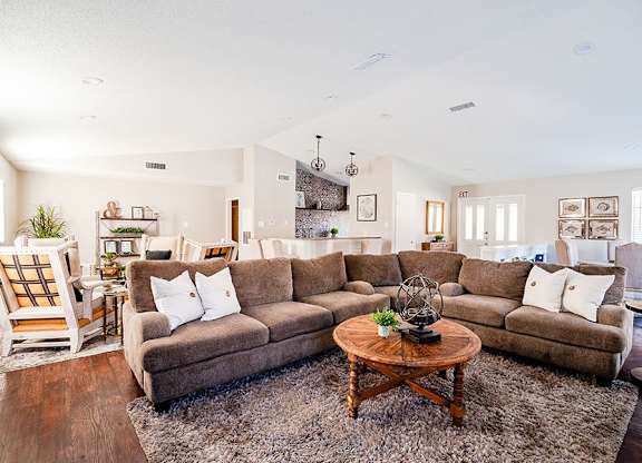 A living room with a large sectional sofa and a coffee table in the center.