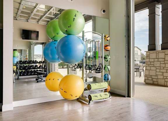 A room with a row of exercise balls of different sizes and colors.