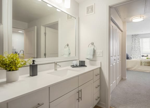 a white bathroom with a large mirror and a sink