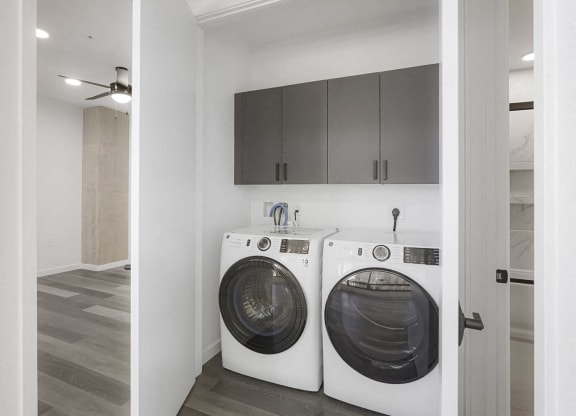 a washer and dryer in a laundry room with white cabinets